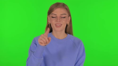 Mujer apuntando a la cámara sobre fondo verde