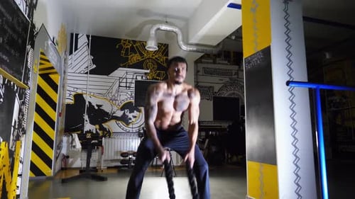 Muscular Afro American Sportsman Training with Battle Ropes at Fitness Centre Strong African Athlete