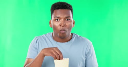 Green screen, face and black man eating popcorn while watching movie, film