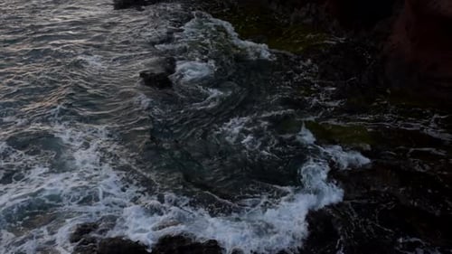 View of the Sea Waves at Sunset From a Cliff Top with a Man Walking on the Top