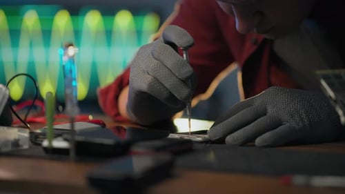 To correct. An electronic technician wearing protective gloves focuses on using a screwdriver in an