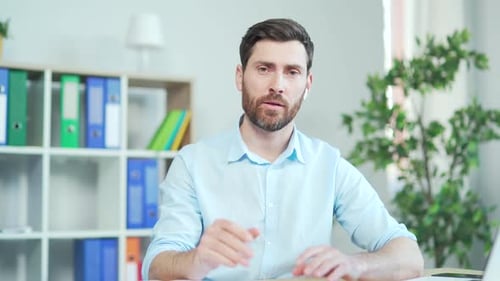 A bearded man listens to an online seminar, meeting, conference or lecture while looking in