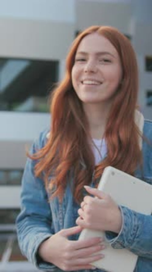 Young Ginger Beautiful Happy Young Girl Student with Tablet Walking Outside Near University Campus