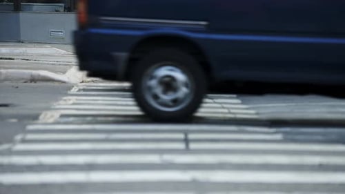 Cars and motorcycles crossing in front of pedestrians waiting to cross the crosswalk of a big city i