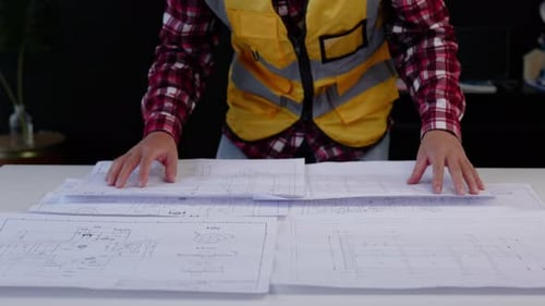 Close up of hands working for cost estimating on floor plan drawings.