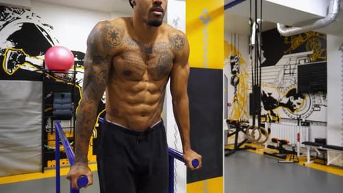 Strong Black Guy Training Abdominal Muscles on Parallel Bars at Gym Afro American Sportsman