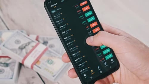 Trader Analyze Cryptocurrency Prices on Smartphone Above Table with Dollars