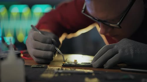 A mechanic uses his skills and experience to disassemble a smartphone at an electronics service