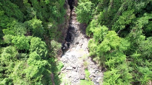 Ein kleiner Wasserfall zwischen Felsen und grünem Dschungel