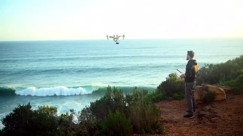 Drone, technology and man with photography on beach filming nature, water or landscape