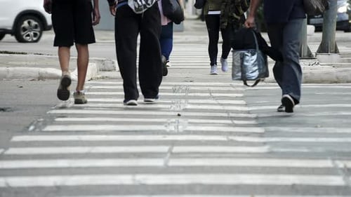 Crowd of pedestrians crossing a street by the crosswalk of a big city in daylight filmed in slow mot