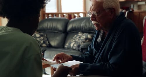 Home caregiver shares health information brochure with senior man at home