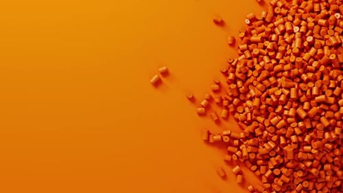 Closeup Top View on Orange Plastic Polypropylene Granules Heap Rotating on Orange Backdrop