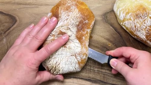 A freshly baked, delicious loaf of homemade ciabatta is cut lengthwise into two halves