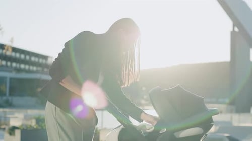 In the Park Young Woman Stand at Sunlight with a Stroller Near Lake Looking on Baby Feel Happy