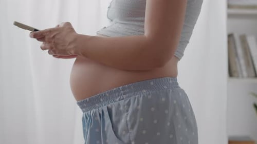 Pregnant. A young parent in home clothes full of love holds a touch phone in a private home. General