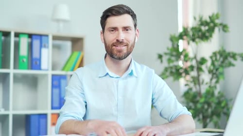 A bearded man listens to an online seminar, meeting, conference or lecture while looking into