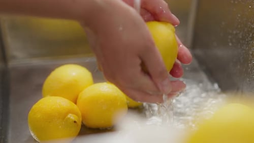 Half of a lemon, pregnant woman concentrated hands wash lemons at home kitchen workplace