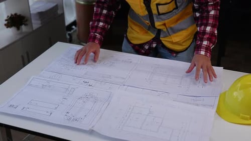 Close up of hands working for cost estimating on floor plan drawings.