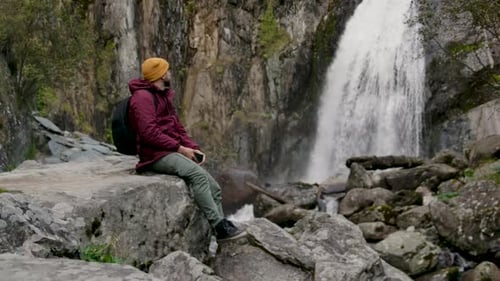 Calm Hiking Male Sitting and Relaxing at Beautiful Waterfall Viewpoint Concept