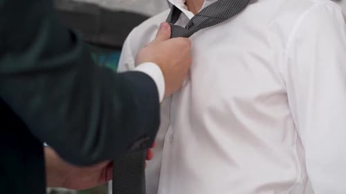 Elegant Man Adjusting Groom's Tie at Wedding