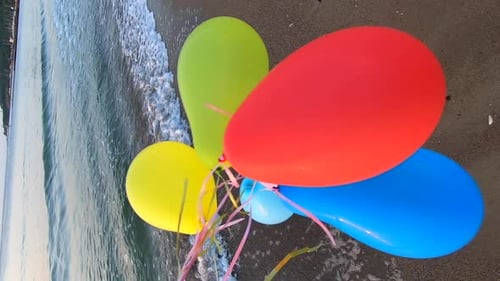Person Playing Many Colorful Balloons on Sandy Beach of Seashore Near Sea Waves