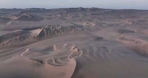 Aerial view of a drone flying over desert massive sand dunes at sunrise. view on the abstract wavy p