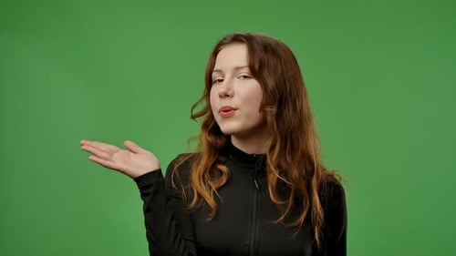 Adolescente posando ante la cámara y lanza un beso al aire con expresión positiva aislada en Chroma Key Green