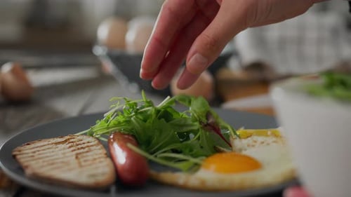 Kitchen. A woman cook in home clothes puts vegetables salad on a plate in the kitchen at home