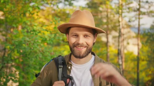 Portrait of Joyful Male Traveler Wearing Backpack and Summer Hat Smiling on Camera Outside Handsome