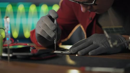 Equipment. A repairman uses skills and experience to apply a screwdriver in an electronic workshop