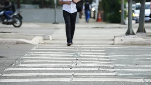 Pedestrian crossing a street by the crosswalk of a big city in daylight filmed in slow motion in 4K
