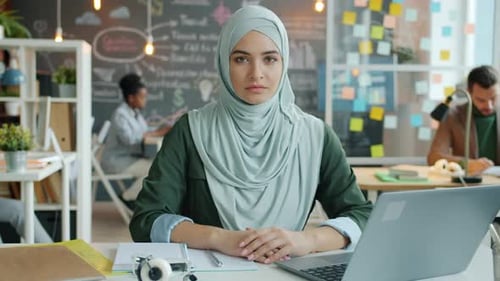 Slow Motion Portrait of Muslim Girl Office Worker Wearing Hijab Sitting at Desk in Office