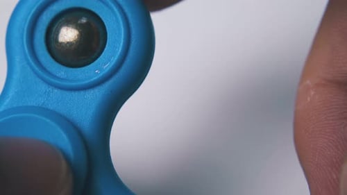 Man Plays with Bright Blue Spinner on Light Background