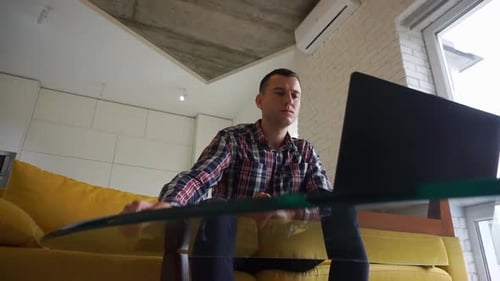 Serious confident and focused young man freelancer works at a laptop