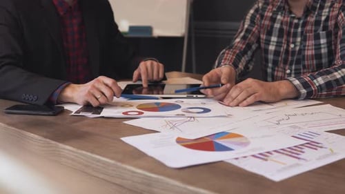 Two Businessmen Analyze the Graphs