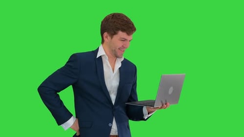 Smiling Young Businessman Using Laptop While Standing on a Green Screen, Chroma Key