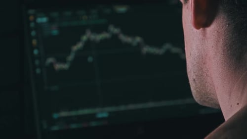 Trader Analyzes Cryptocurrency Charts on a Laptop Screen in the Dark