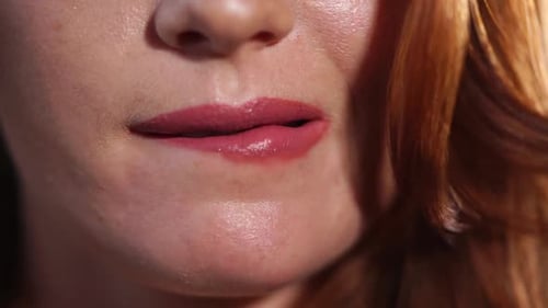 Gros plan des lèvres d'une femme qui mord érotiquement le bas de la lèvre