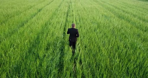 A Man in a Business Suit Runs Across the Field Shooting From a Height of Flight