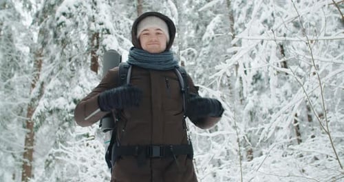 Happy Male Traveler Backpacker Standing in Winter Forest Smiling and Looking Around