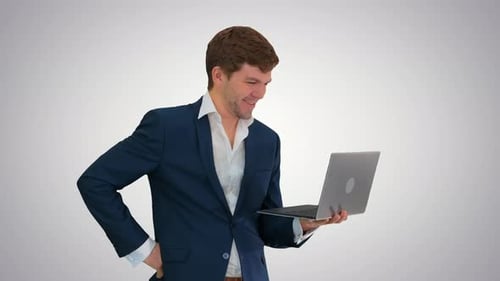 Smiling Young Businessman Using Laptop While Standing on Gradient Background.