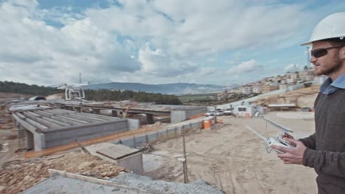 Man flying a drone for construction survey in a large highway construction site