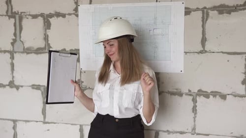 The girl engineer builder is checking the drawings and rejoices at the success.