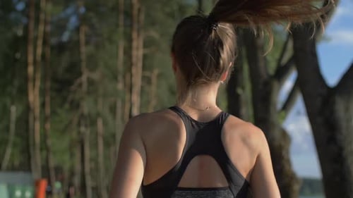 Young woman with a slender figure in gymnastics clothes running in the park