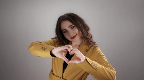 Portrait of Young Caucasian Woman Showing Heart Shape By Her Hands on White Background in Slowmo